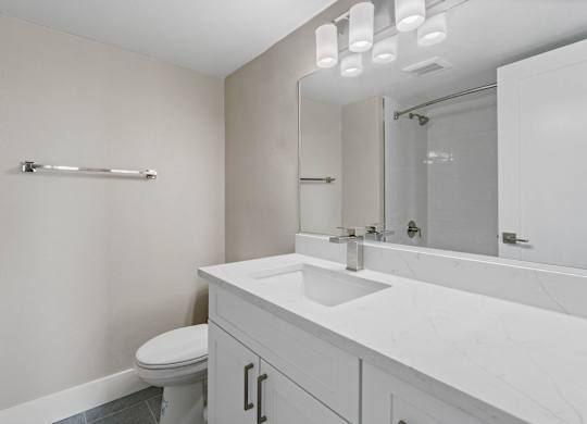 A white bathroom with a toilet, sink, and mirror.