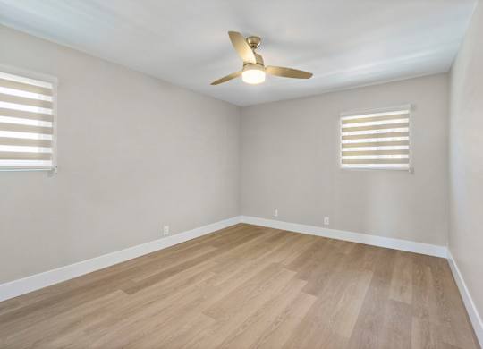 A room with a ceiling fan and wooden flooring.