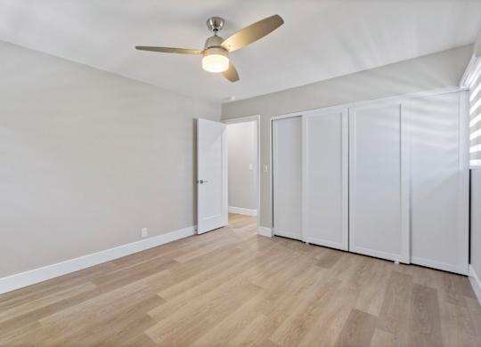 A room with a ceiling fan and wooden flooring.