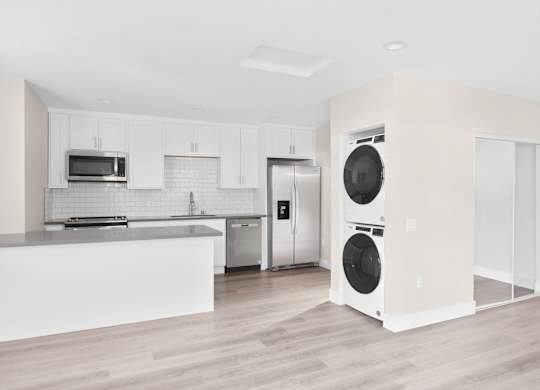 A modern kitchen with a white countertop and stainless steel appliances.