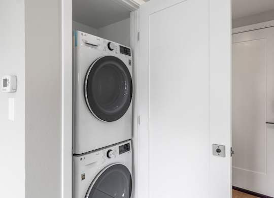 A white washing machine is in a white cabinet.