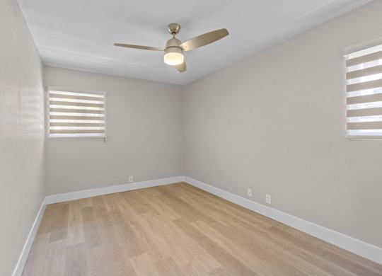 A room with a ceiling fan and wooden flooring.