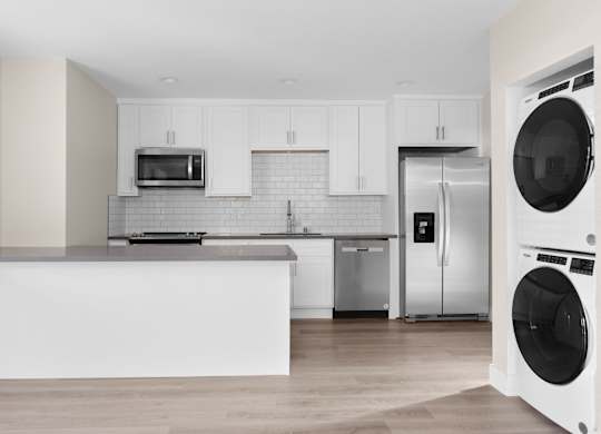 A modern kitchen with a white countertop and stainless steel appliances.