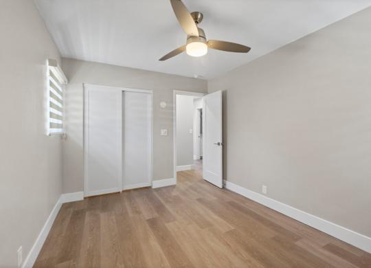 A room with a ceiling fan and wooden flooring.