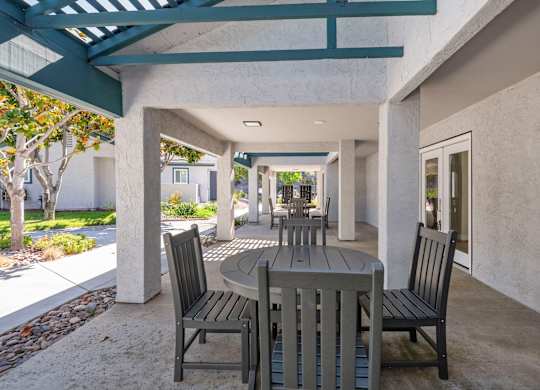A patio with a table and chairs under a roof.