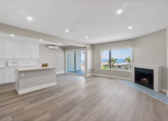 A spacious living room with a fireplace and sliding glass doors leading to a balcony.