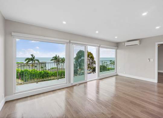 A spacious room with a view of the ocean through large windows.