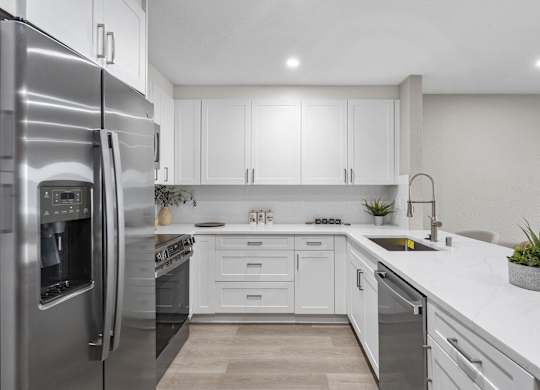 A modern kitchen with a stainless steel refrigerator and white cabinets at Tamarack Sands Apartment Homes, California