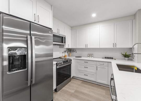 A modern kitchen with a stainless steel refrigerator and white cabinets at Tamarack Sands Apartment Homes, Carlsbad, California