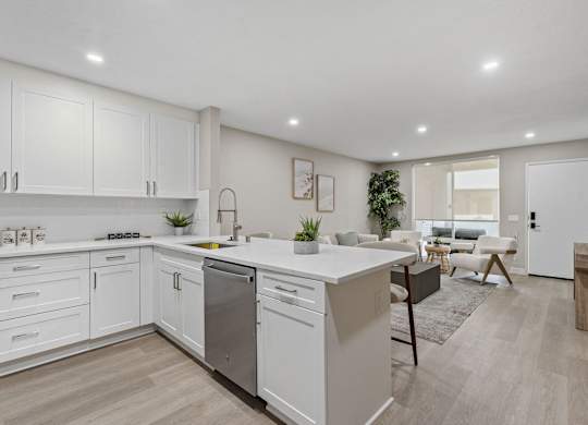 A modern kitchen with white cabinets and a wooden floor at Tamarack Sands Apartment Homes, Carlsbad