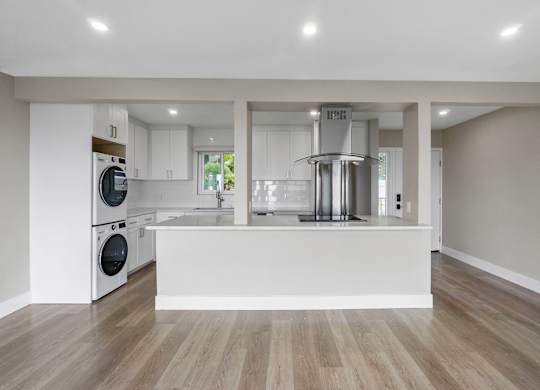 A modern kitchen with a white countertop and wooden flooring.