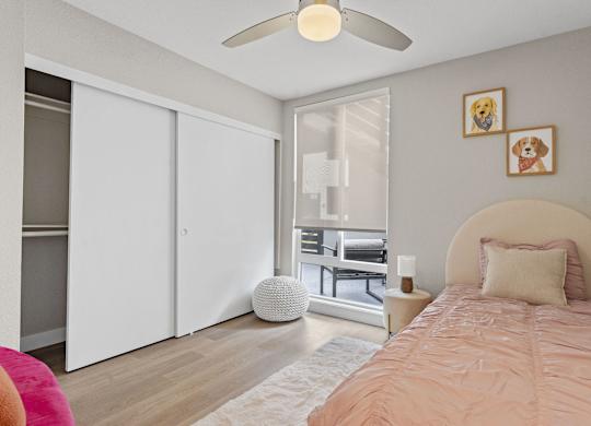 A bedroom with a bed, a ceiling fan, and a window with blinds at Tamarack Sands Apartment Homes, Carlsbad