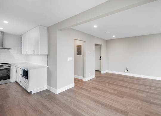 A kitchen with white cabinets and a wooden floor.