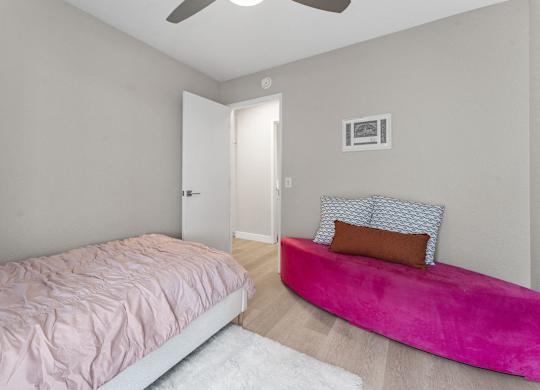 A bedroom with a pink bed and a pink bench at Tamarack Sands Apartment Homes, Carlsbad, 92008
