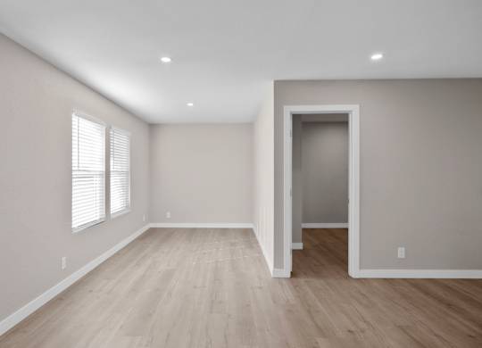 A room with wooden flooring and a doorway leading to another room.