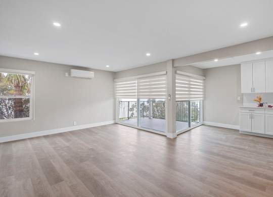 A spacious room with wooden flooring and white walls.
