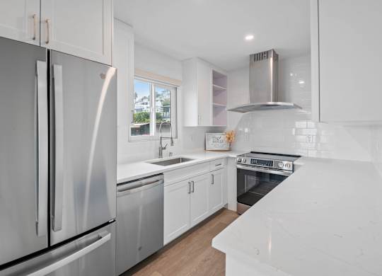 A modern kitchen with white appliances and cabinets.