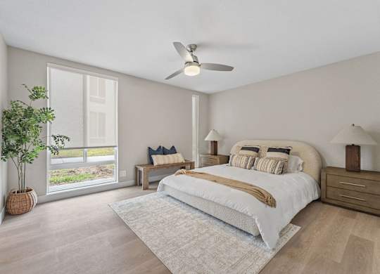 A bedroom with a large bed, a ceiling fan, and a potted plant at Tamarack Sands Apartment Homes, Carlsbad
