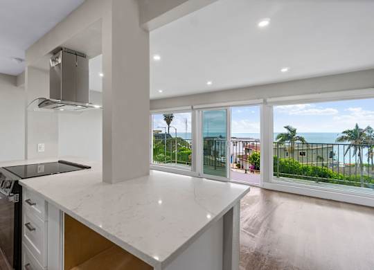 A modern kitchen with a large island and a view of the ocean.