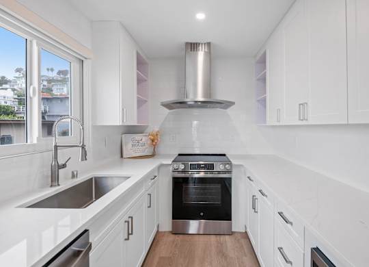 A modern kitchen with white cabinets and stainless steel appliances.