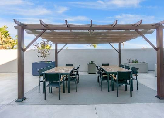 A patio with a table and chairs under a wooden pergola.at The Reserve La Mirada, California, 90638
