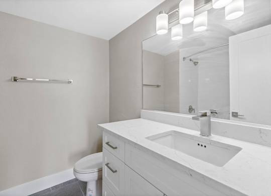 A white bathroom with a toilet, sink, and mirror.