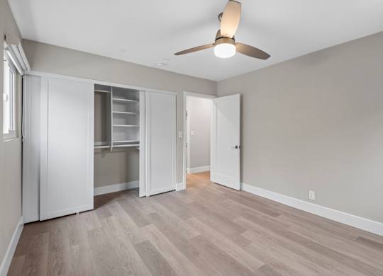 A room with a ceiling fan and a wooden floor.