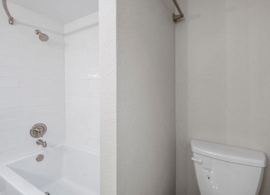 A white toilet in a bathroom with a white tub and shower.