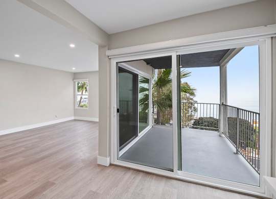 A room with a sliding glass door leading to a balcony.