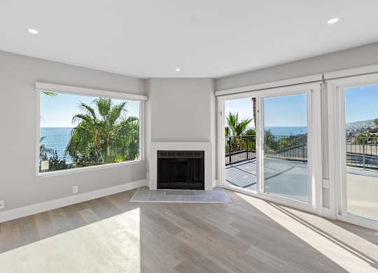 A spacious living room with a fireplace and sliding glass doors leading to a balcony.at Ocean Edge @ Laguna Beach, Laguna Beach, 92651