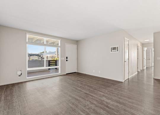 A spacious room with a large window and wooden flooring.