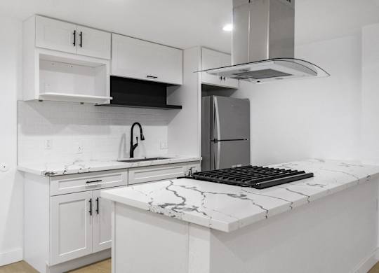 A kitchen with white cabinets and a marble countertop. at Torrance Gateway Apartments, California
