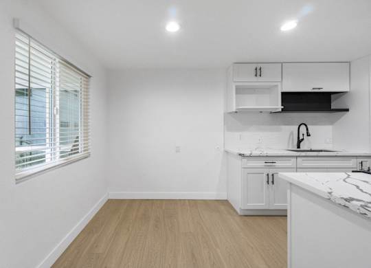 A kitchen with white cabinets and a marble countertop. at Torrance Gateway Apartments, Torrance