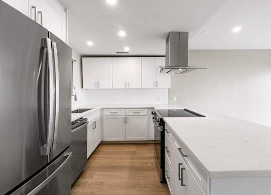 A modern kitchen with a stainless steel refrigerator and white cabinets.