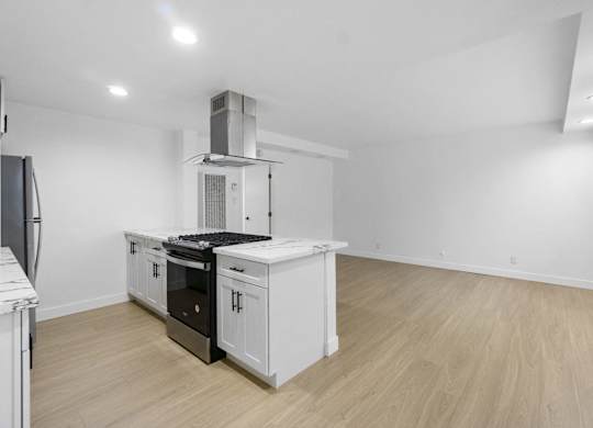 A kitchen with white cabinets and a black stove top oven. at Torrance Gateway Apartments, California