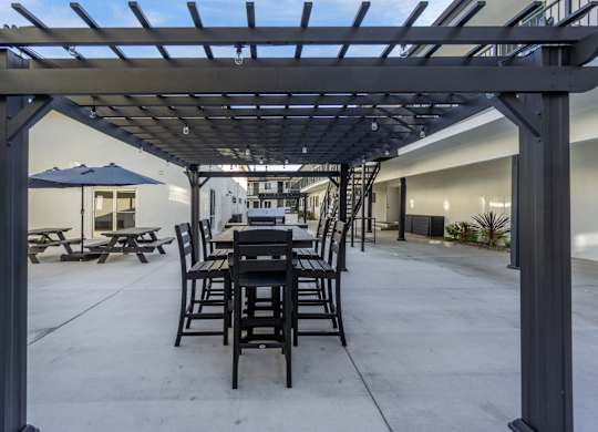 A patio with a table and chairs under a pergola. at Torrance Gateway Apartments, California