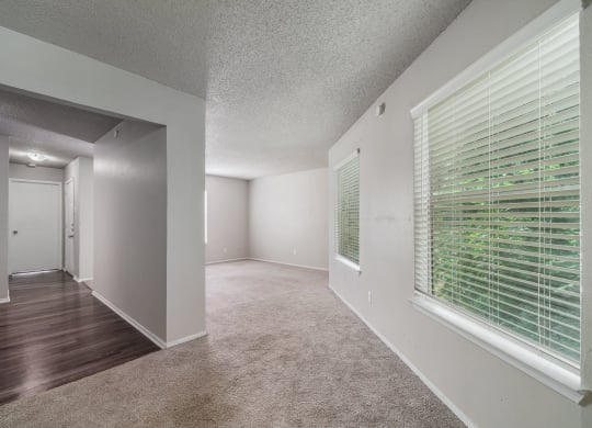 the spacious living room and dining room of an apartment with a large window  at Shadow Ridge, Arlington, 76013
