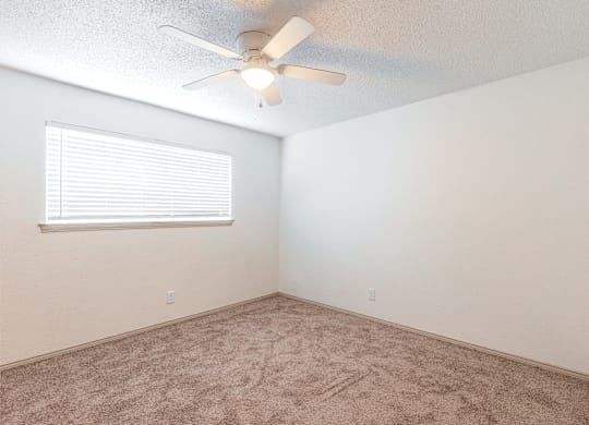 an empty room with a ceiling fan and a window