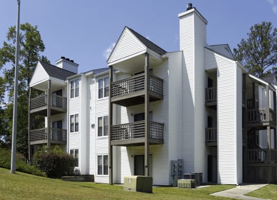 an apartment building with white siding and balconies on a sunny day