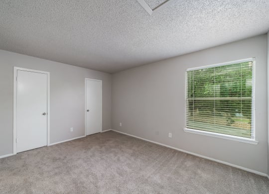 an empty bedroom with a large window and carpeted flooring  at Shadow Ridge, Arlington, Texas