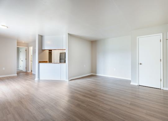 A spacious room with wooden flooring and white walls.