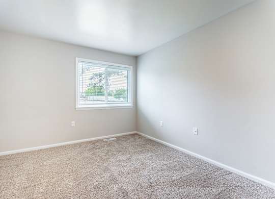 A room with a window and carpeted floor.