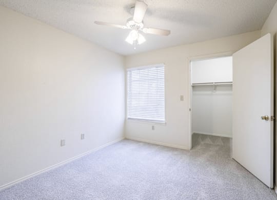 A room with a ceiling fan and a door leading to another room.