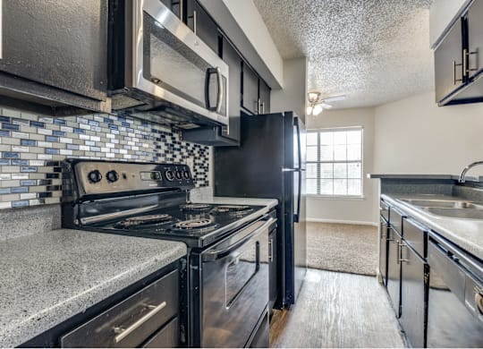 A kitchen with a black stove top oven and black cabinets.