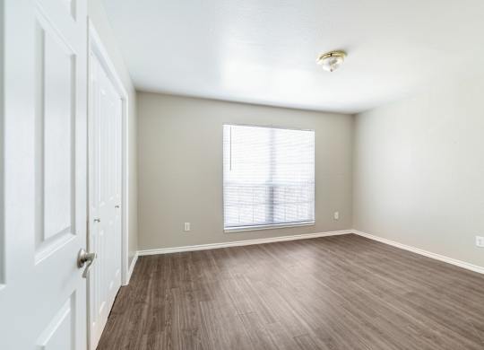 Spacious bedroom with laminate flooring and blinds at Lumina Apartments, Dallas, TX