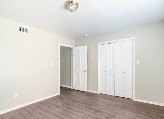 Bright bedroom with closet and wood floors at Lumina Apartments, Dallas, Texas