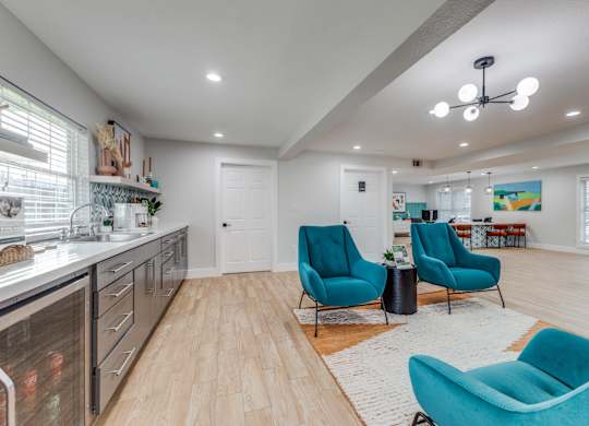 A kitchen with a white counter top and blue chairs. at Carisma, Dallas