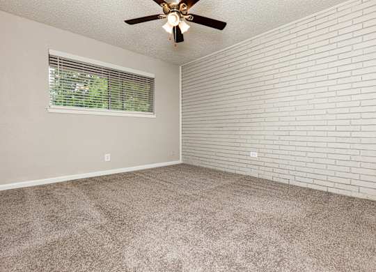 A room with a ceiling fan and a window with blinds.