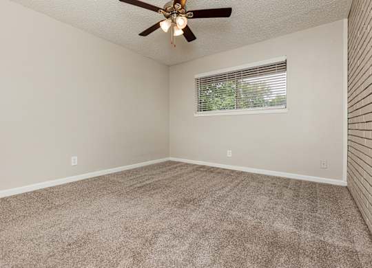 A room with a ceiling fan and a window with blinds.