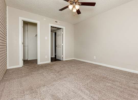 A room with a ceiling fan and carpeted floor.